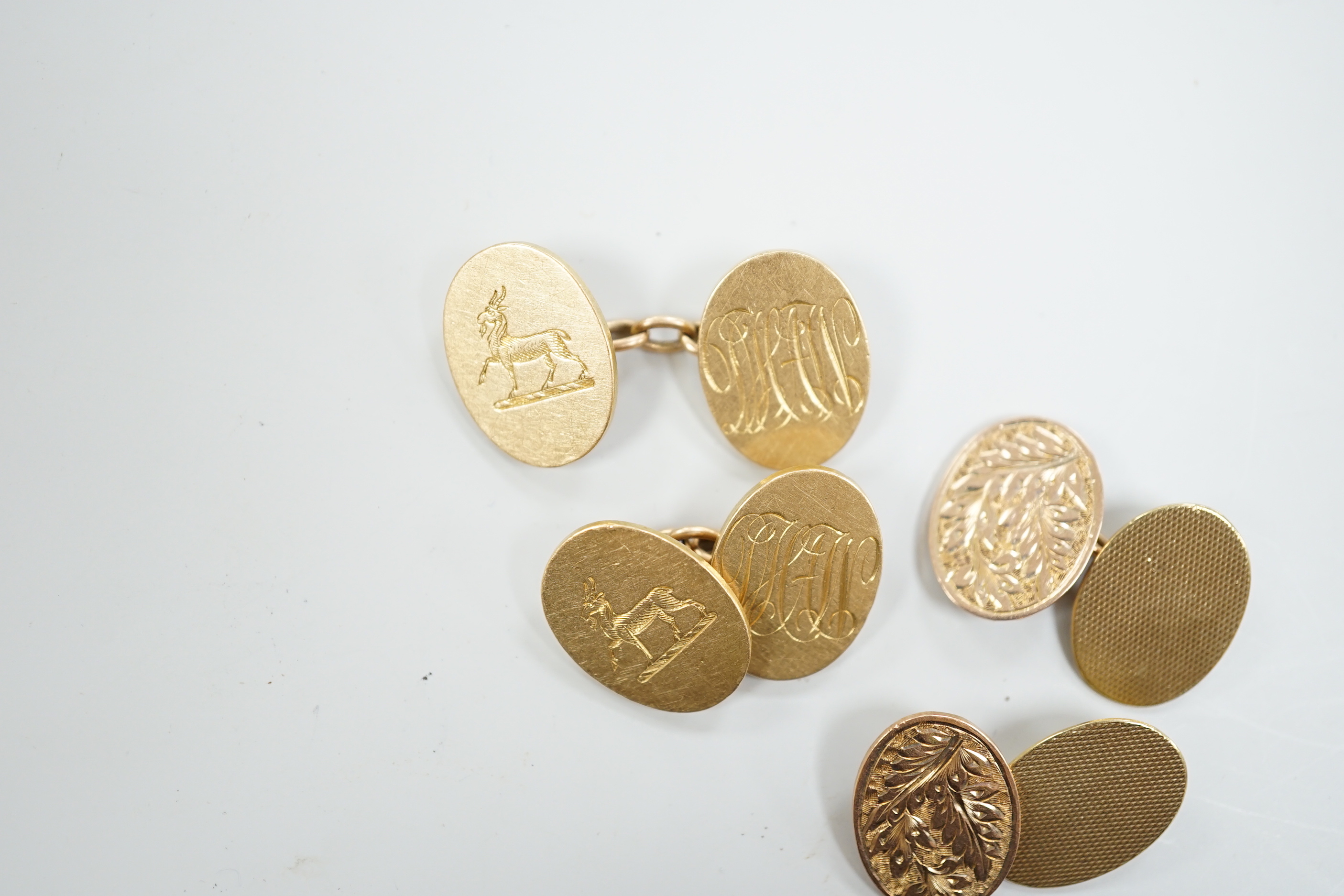 A pair of George V 18ct gold oval cufflinks, with engraved crest and initials, G.H. Johnstone & Co, Birmingham, 1915, 16.7 grams and a pair of late Victorian engraved 9ct gold oval cufflinks, 6.7 grams.